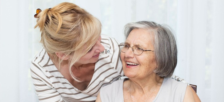 Eine ältere Frau wird von einer jüngeren Frau betreut