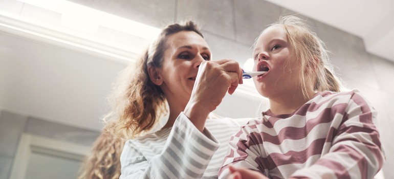 Grundpflege: Eine Mutter hilft ihrem Kind mit Behinderung bei der Zahnpflege