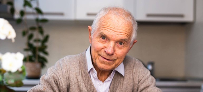 Ein älterer Mann unterschreibt einen Antrag in seiner Küche