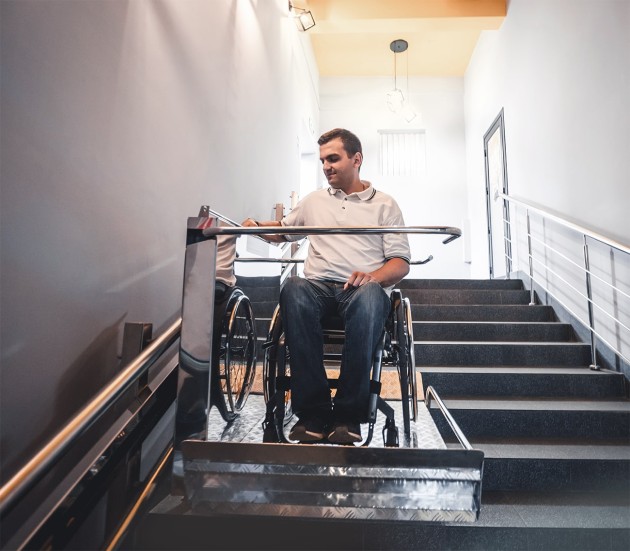 Rollstuhlfahrer fährt auf Plattformlift