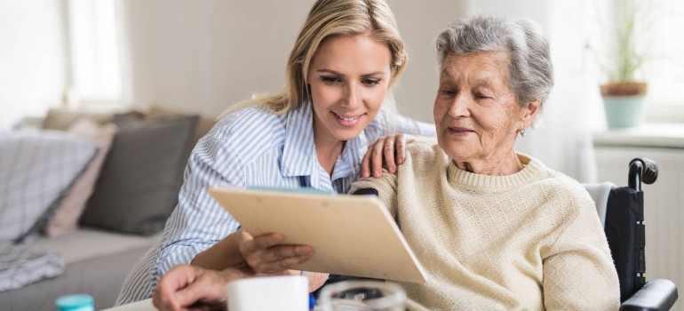 Eine ältere Dame im Rollstuhl und ihre Tochter kümmern sich um Unterlagen