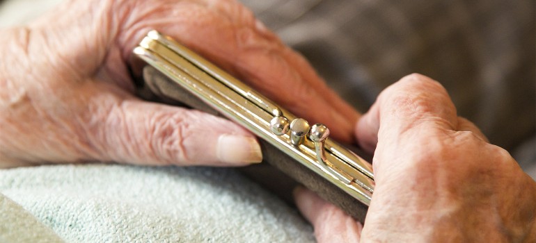 Zwei Hände einer älteren Person halten eine Geldbörse