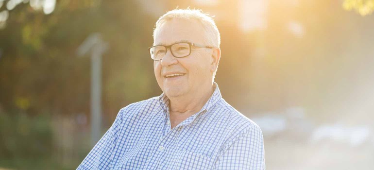 Ein älterer Mann mit Brille lächelt im Sonnenuntergan