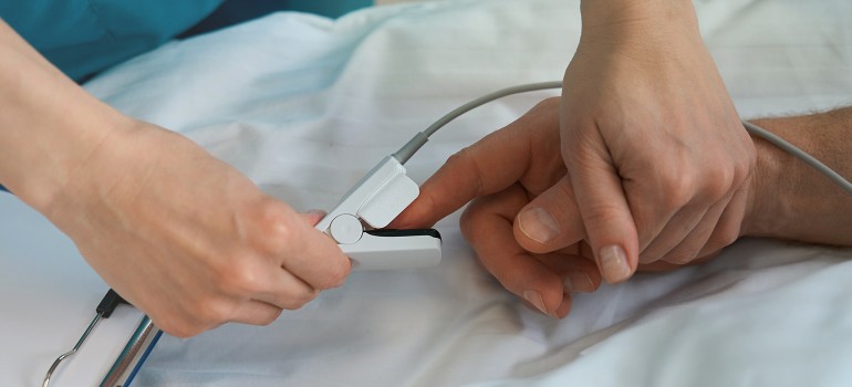 Intensivpflege: Ein Patient erhält einen Pulsmesser an den Finger