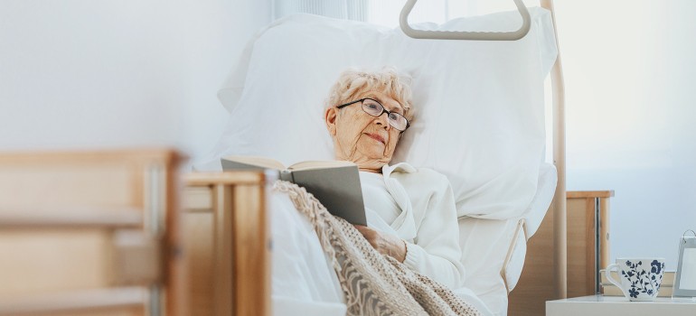 Kurzzeitpflege: Ältere Dame liegt in einem Pflegebett