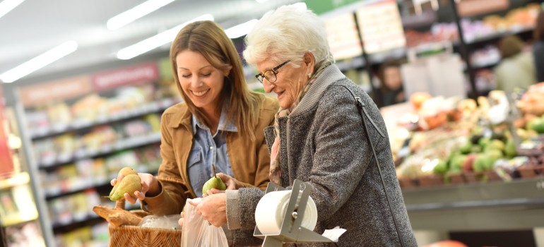 Eine Nachbarin hilft einer älteren Dame beim Einkauf