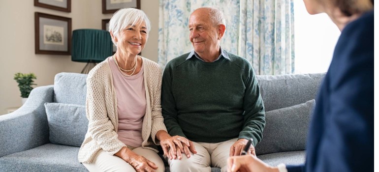 Ein älteres Paar sitzt im Wohnzimmer bei einer Pflegebegutachtung