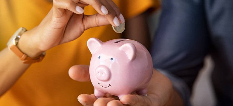 Jemand steckt eine Münze in ein Sparschwein