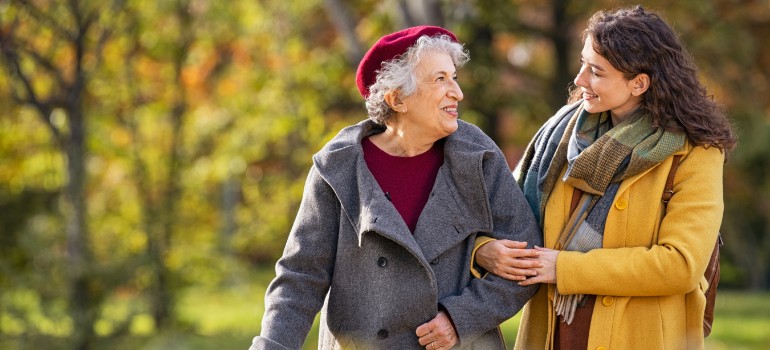 Eine junge Frau geht mit einer älteren Frau am Arm spazieren