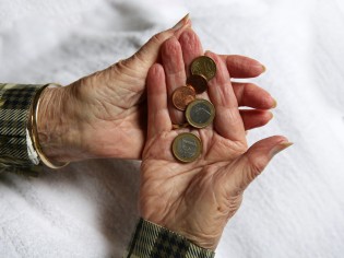 Zwei ältere Hände halten einige Münzen in der Hand