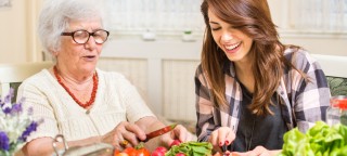 Eine Angehörige bereitet zusammen mit einer älteren Frau Essen zu