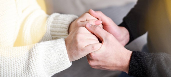 Eine Person hält die Hände einer anderen Person