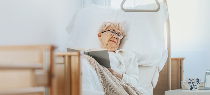 Kurzzeitpflege: Ältere Dame liegt in einem Pflegebett