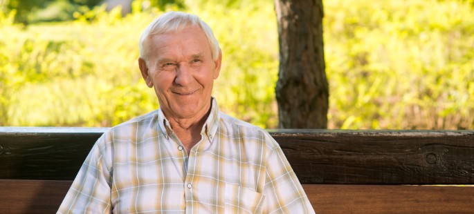 Ein Mann mit einem Notrufknopf sitzt auf einer Bank