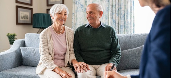 Ein älteres Paar sitzt im Wohnzimmer bei einer Pflegebegutachtung